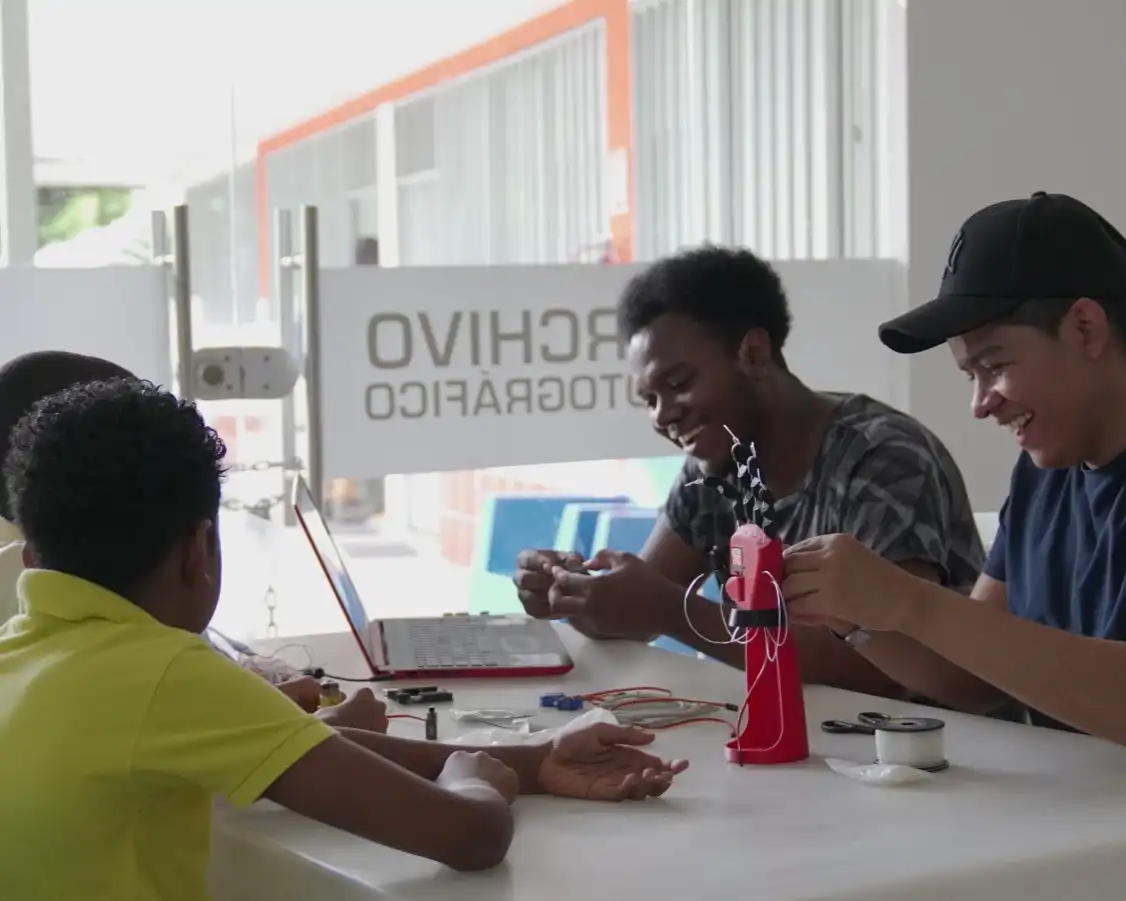 Estudiantes de CREA divirtiendose mientras realizan el ensamble de un brazo robótico