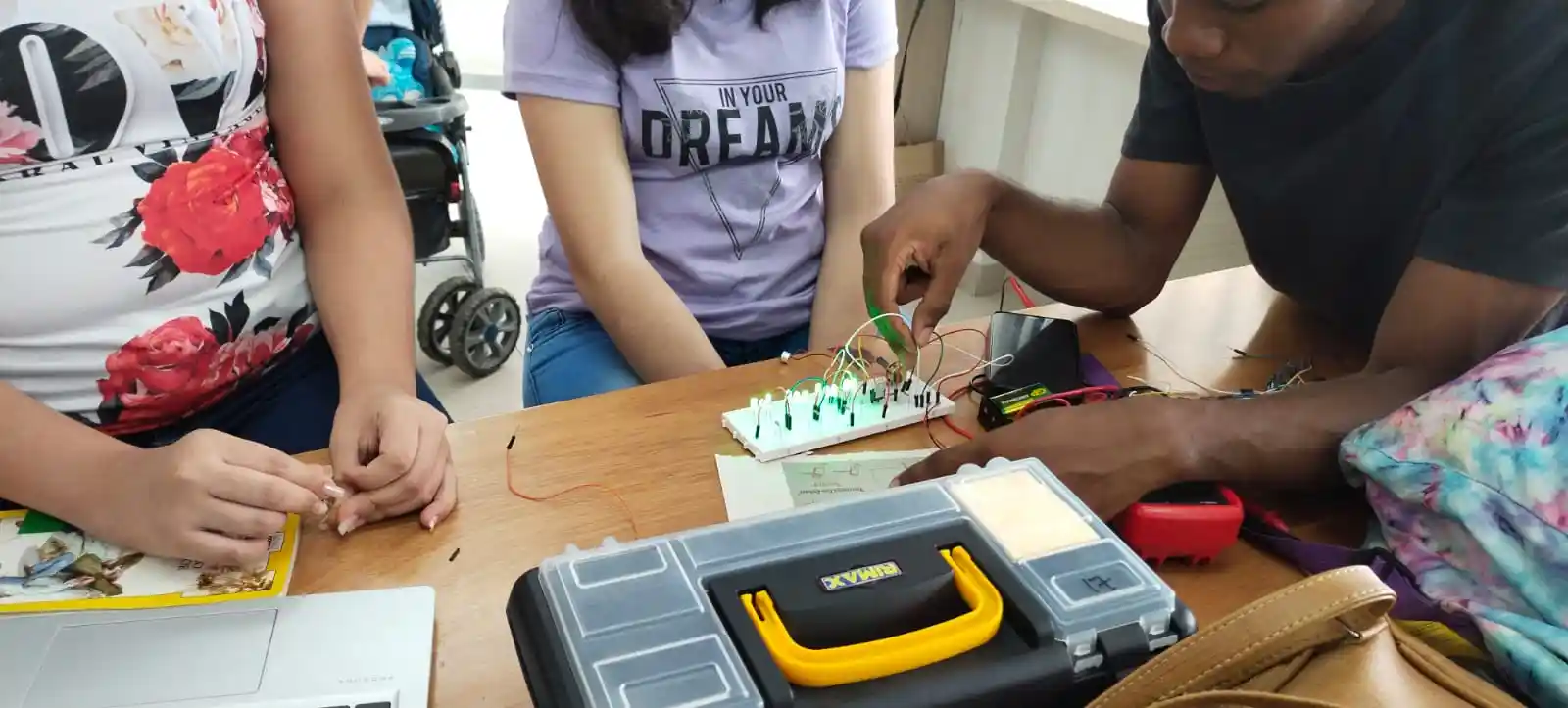 grupo de alumas y alumno de CREA realizando la conexión de circuito de LEDs en protoboard