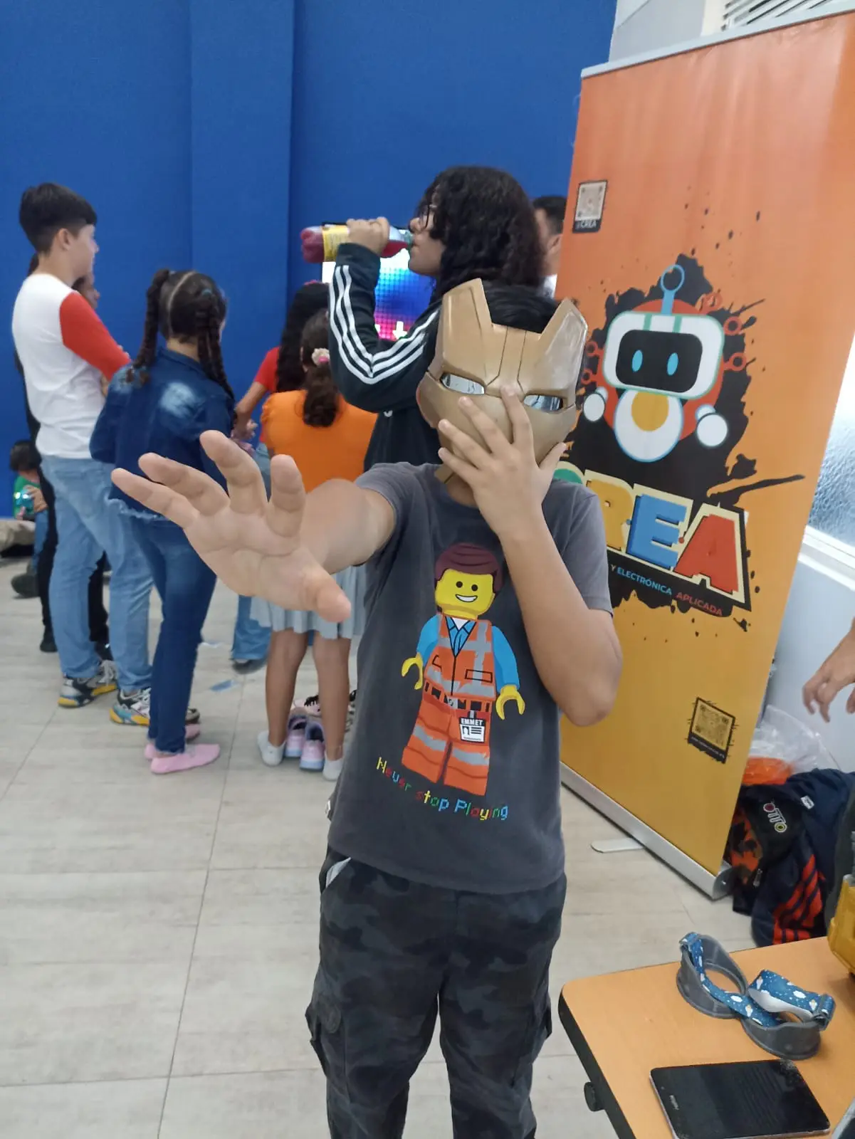 niño emocionado con la máscara de IronMan impresa en 3D posando al frente del letrero de CREA durante un evento en el instituto ColomboAmericano de Cali